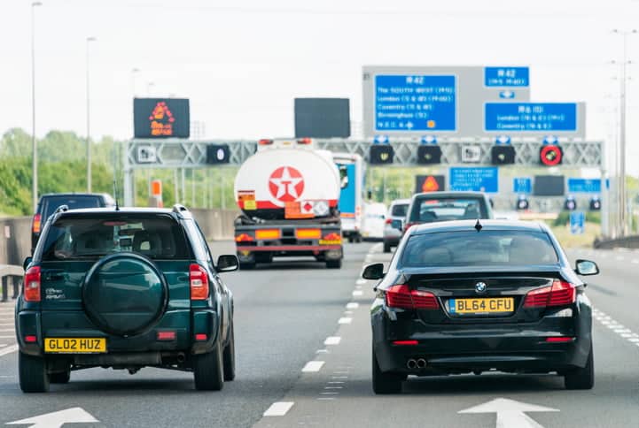 M42 Motorway, UK - Rear view of busy traffic, with a group of signs in the background on the M42 motorway in the English Midlands.