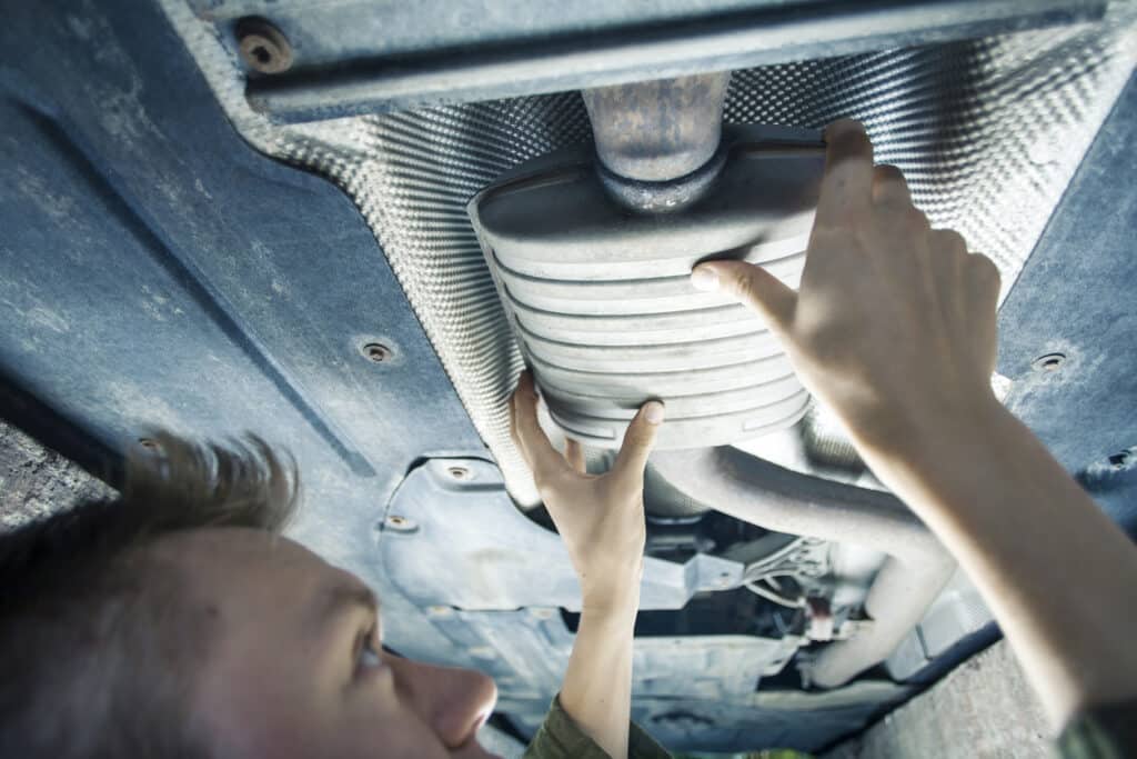Male mechanic fitting something under a car