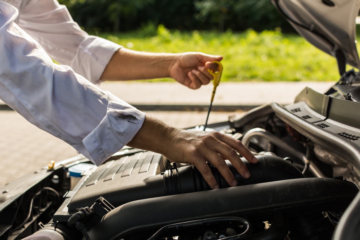 Cropped image of hands testing oil from a car engine