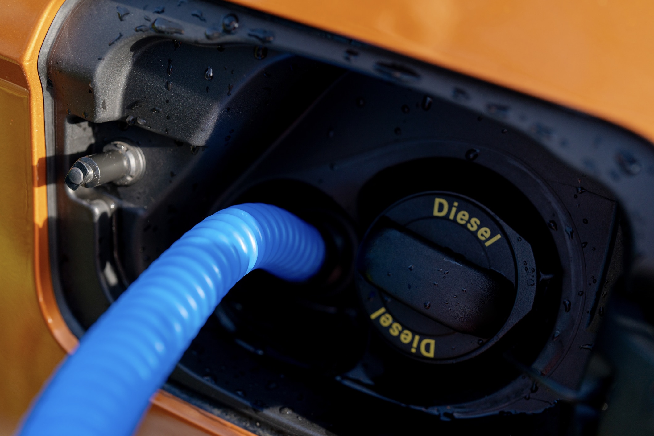 Driver filling adblue tank of the modern orange diesel car
